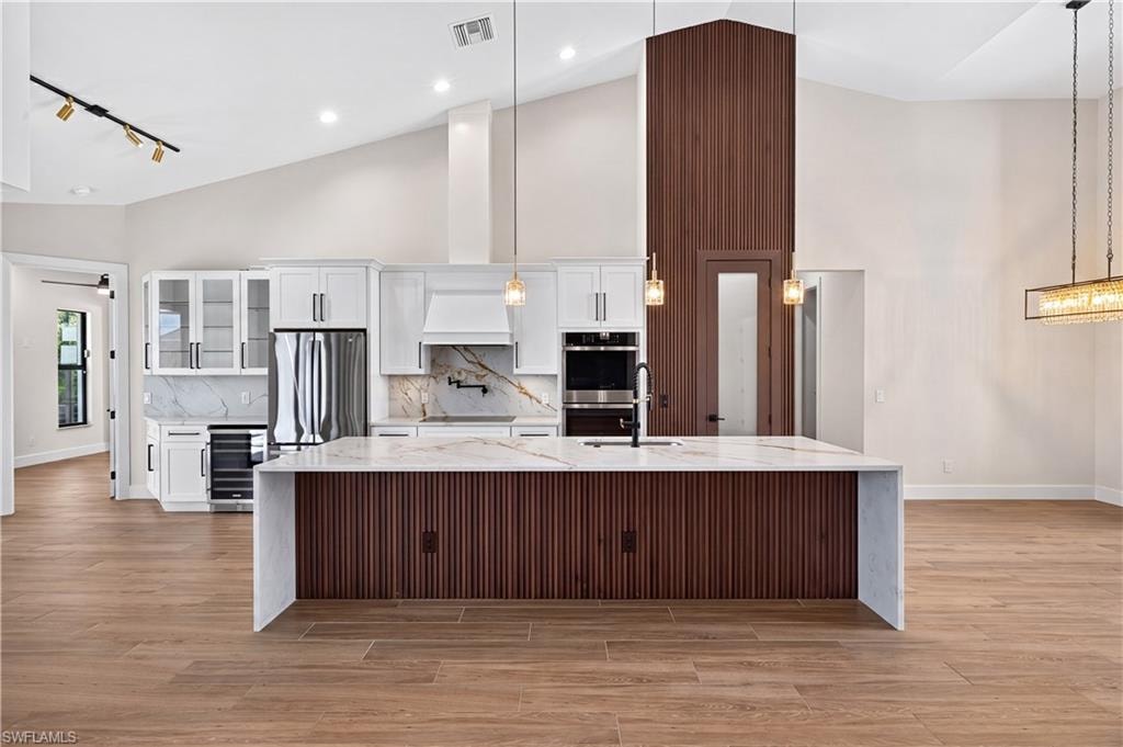 Expansive kitchen featuring a waterfall island with ribbed wood paneling and a light-toned countertop