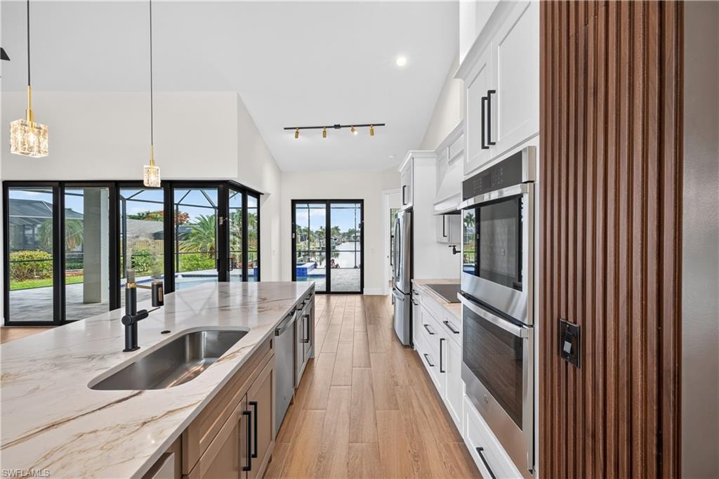 Contemporary kitchen featuring a large island with an undermount sink, integrated beverage refrigerators, and pendant lighting
