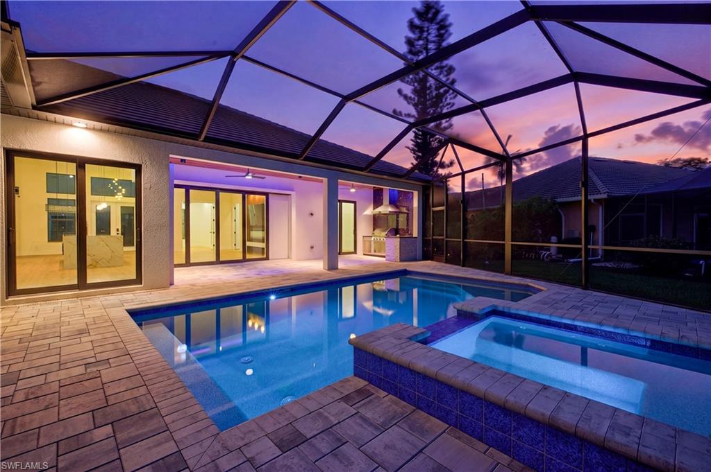Screened lanai featuring a swimming pool, integrated spa with mosaic tile, and stone paver decking