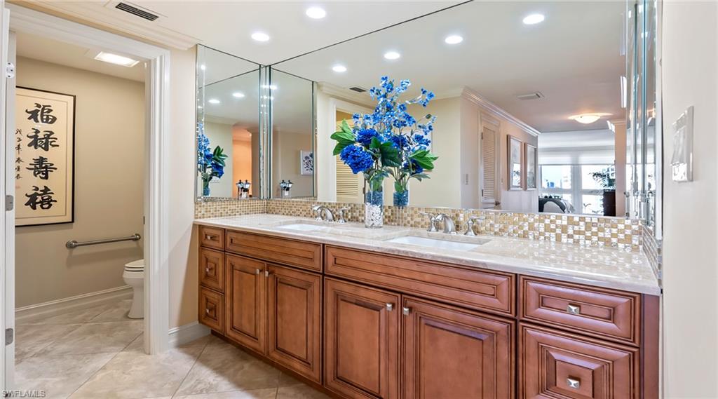Full bath with tasteful backsplash, double vanity, recessed lighting, and crown molding