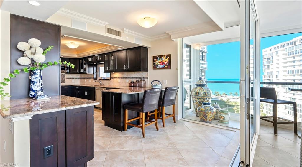 Bar with light stone countertops, backsplash, a water view, expansive windows, and dark cabinets