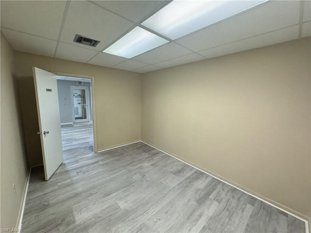 Recessed ceiling lighting, drop ceiling, neutral painted walls, light wood-finish flooring, and white trim