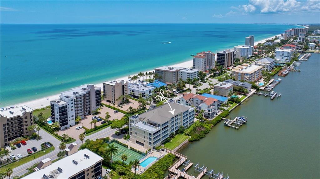 Four-story residential building with multiple private balconies, situated between a coastal beach and a waterway