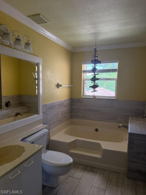 Soaking tub with tiled surround, wood-finish flooring, a single window, and a vanity with a drop-in sink
