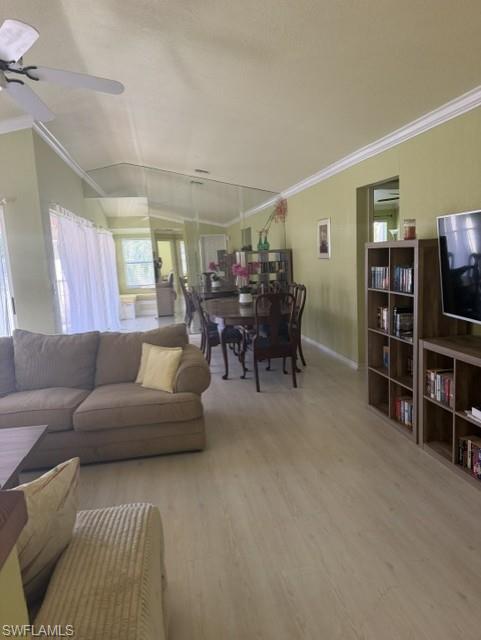 Open-concept living and dining area featuring wood-finish flooring, a vaulted ceiling, and crown molding