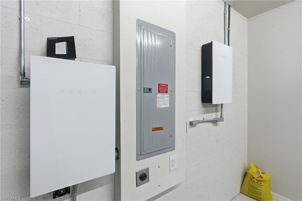 Integrated white-panel energy storage systems with conduit wiring, alongside an electrical service panel and wall outlets