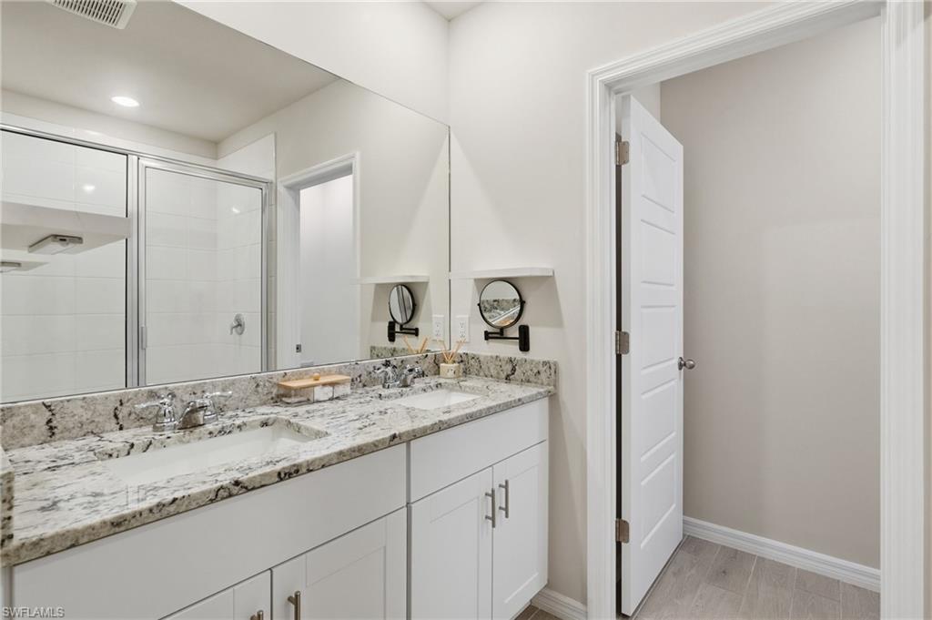 Dual vanity with a stone countertop, chrome hardware, and undermount sinks
