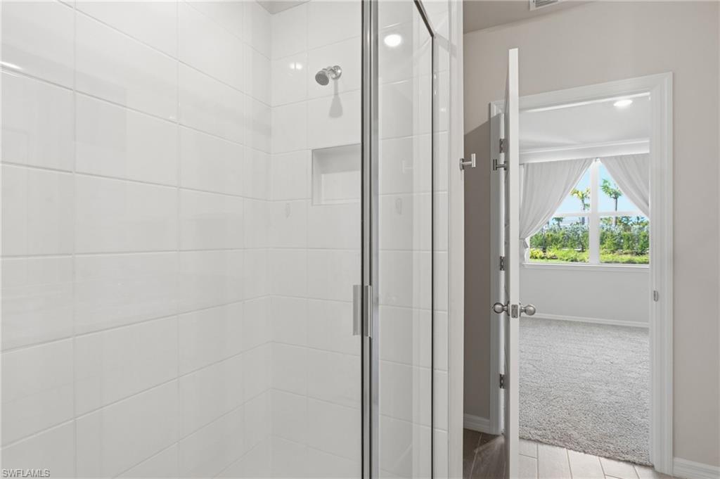 Shower enclosure featuring white subway tile, a recessed niche, and a chrome showerhead