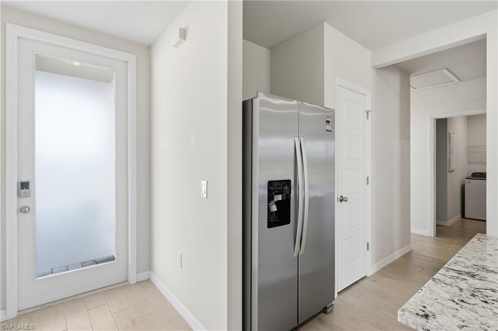 Stainless steel side-by-side refrigerator, white paneled doors, and light wood-finish flooring