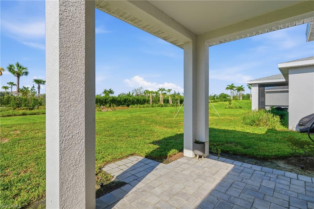 Covered patio with paver flooring, stucco columns, and expansive green space