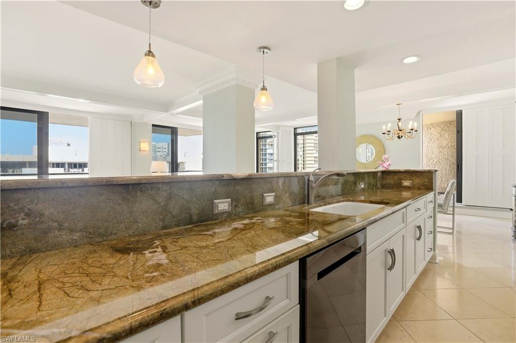 Kitchen featuring decorative backsplash, dishwasher, white cabinets, dark stone counters, and hanging lights