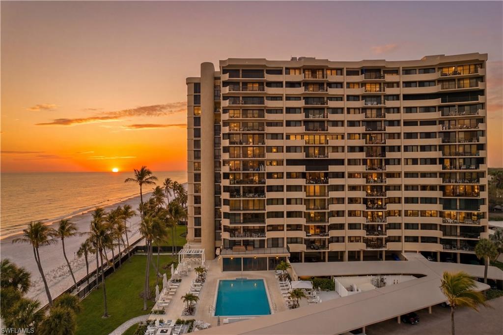 South side of Surfsedge during sunset with an aerial view of the pool, spa fire pit and grilling area