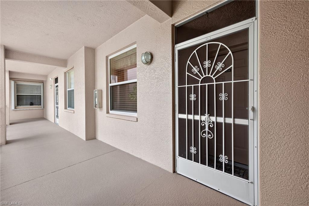 Entryway featuring a decorative security door, textured stucco exterior, and dual-pane windows