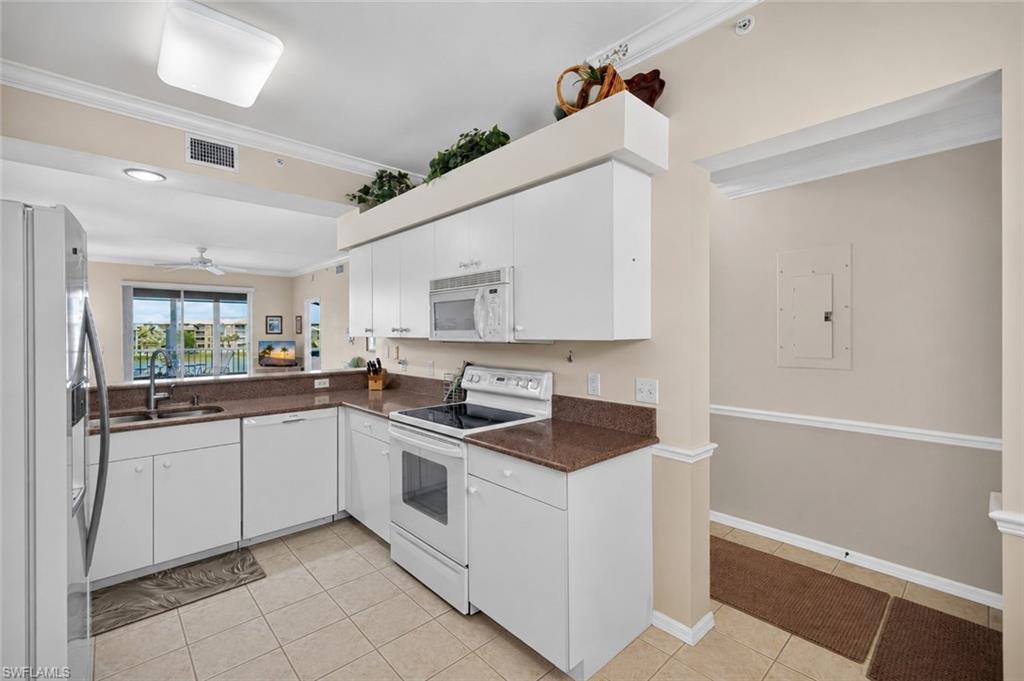 Kitchen featuring white cabinetry, brown solid surface countertops, and white appliances