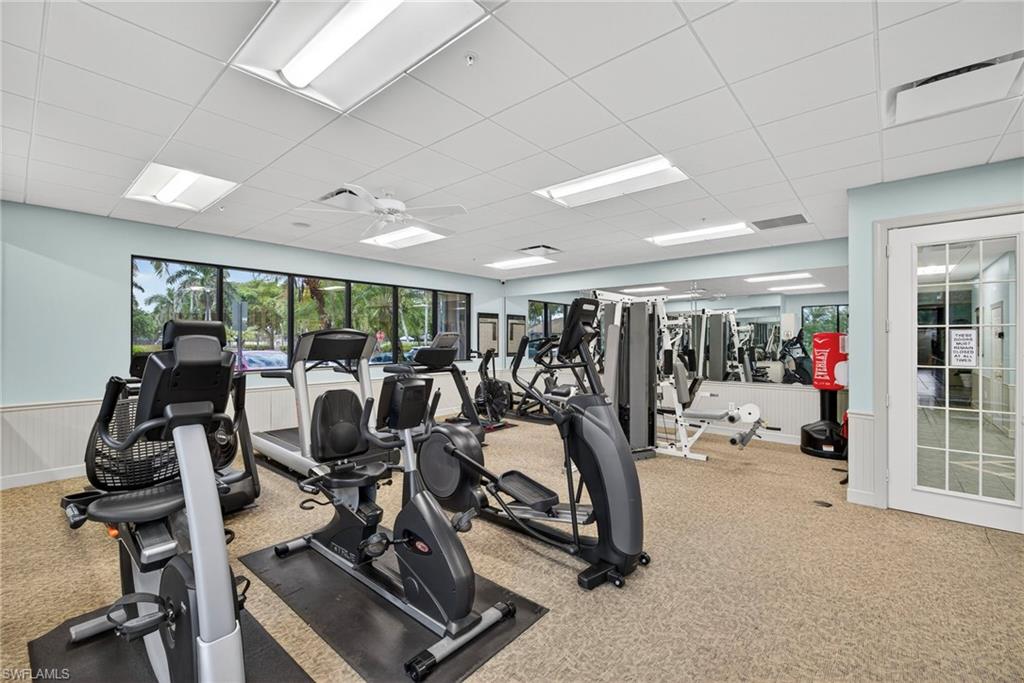 Dedicated fitness room featuring multiple exercise machines, mirrored wall, and large windows