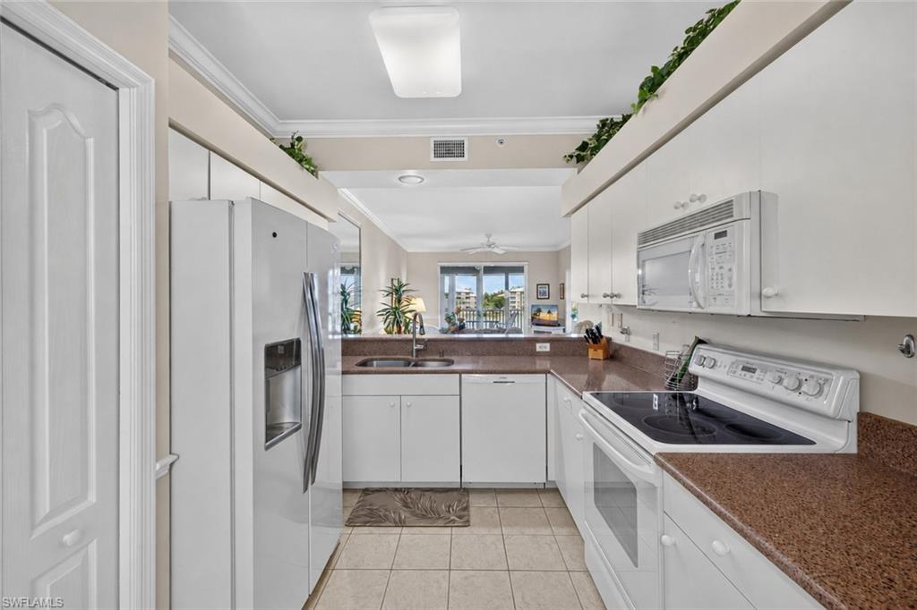Galley kitchen featuring white cabinetry, brown speckled countertops, and tile flooring
