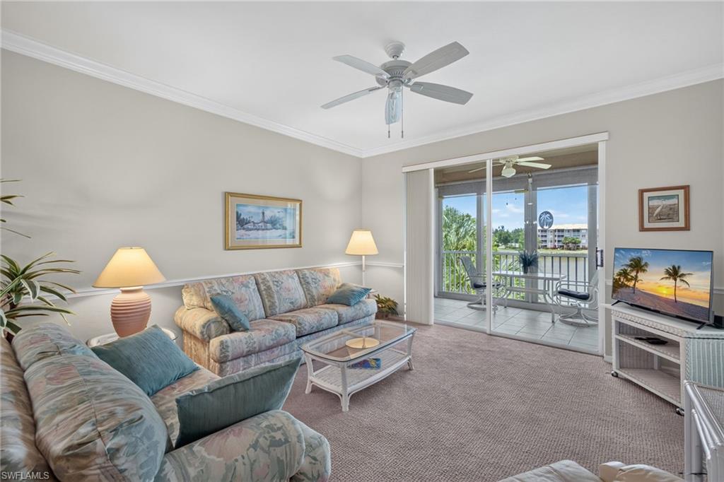 Living area featuring neutral wall tones, crown molding, and a ceiling fan