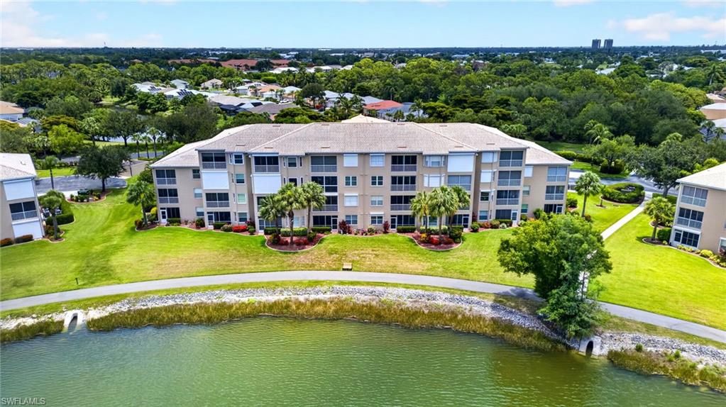 Multi-story condominium building featuring a neutral-toned exterior, multiple screened balconies, and a tiled roof