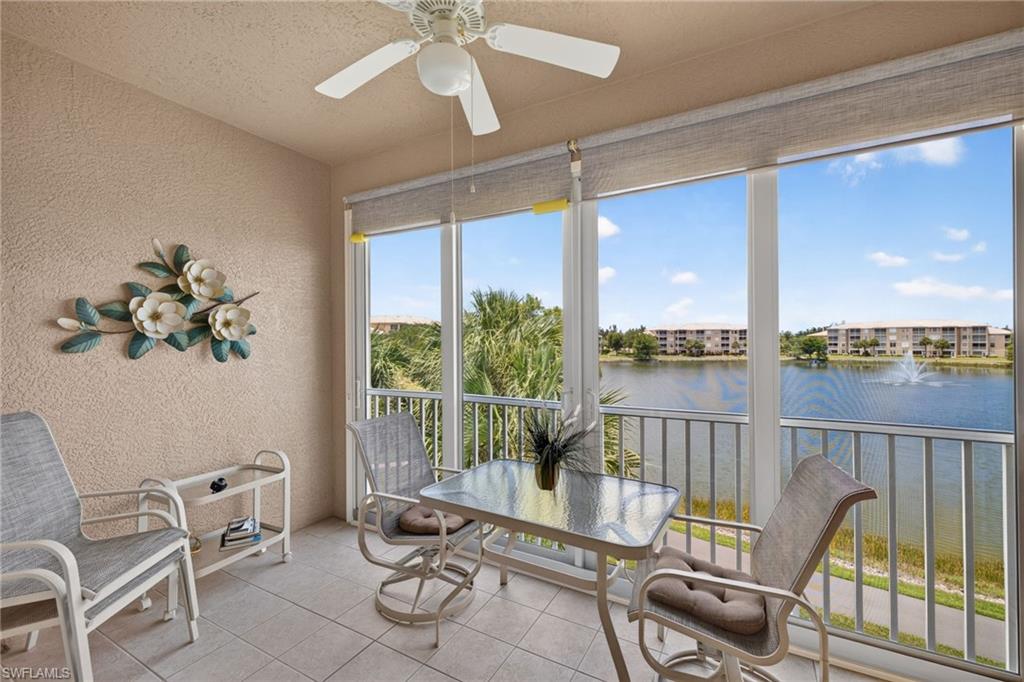 Screened balcony featuring expansive water views, a ceiling fan, and tiled flooring