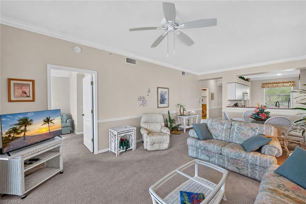 Living room featuring neutral-toned walls, crown molding, and carpeted flooring