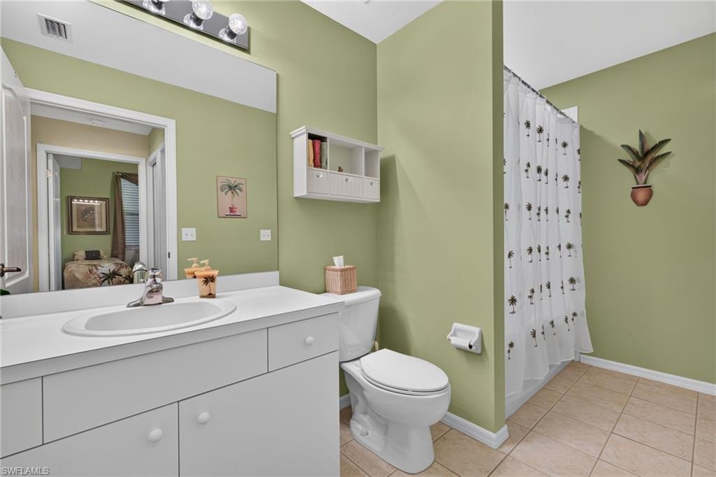 Bathroom featuring a vanity with an integrated sink, a toilet, and a shower with a privacy curtain