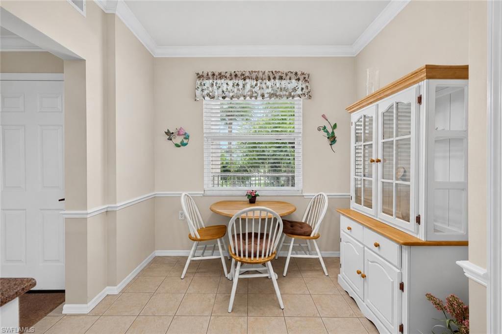 Recessed dining area featuring tile flooring, a window with horizontal blinds, and crown molding