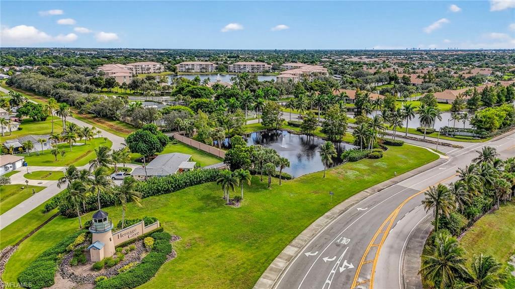 Manicured grounds featuring a decorative lighthouse monument, lush landscaping with palm trees, and a tranquil pond with a fountain