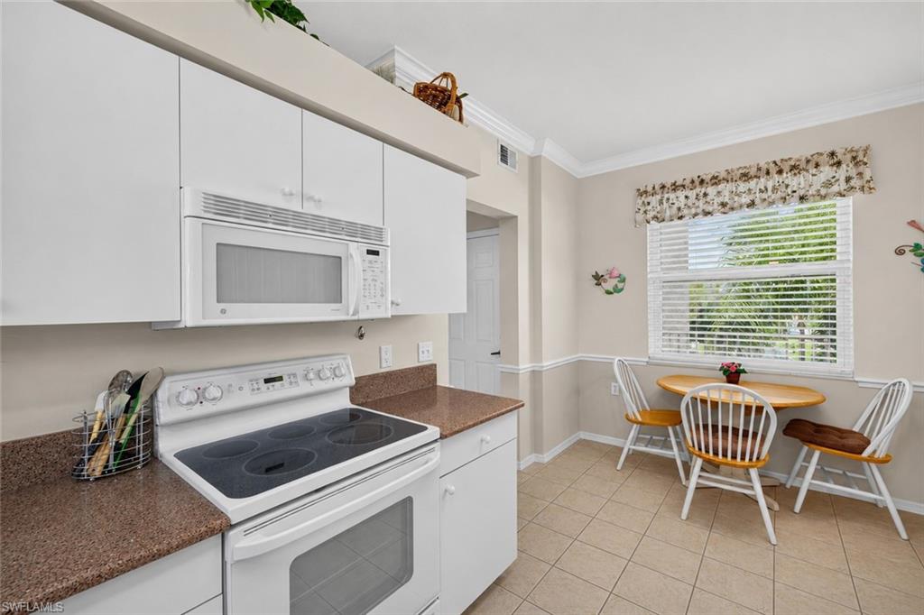 Kitchen featuring white cabinetry, brown granite-look countertops, and an electric range with an overhead microwave