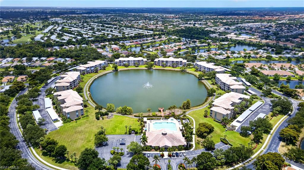 Aerial perspective of a residential community featuring a central lake with a fountain