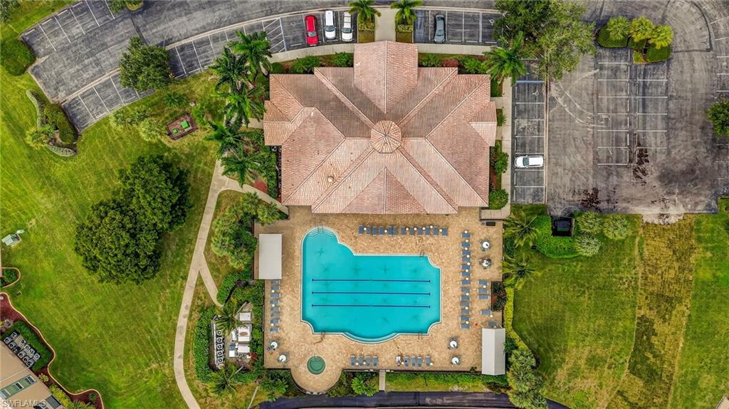 Central swimming pool with a surrounding paved deck, accompanied by a spa, lounge chairs, and a shaded pergola