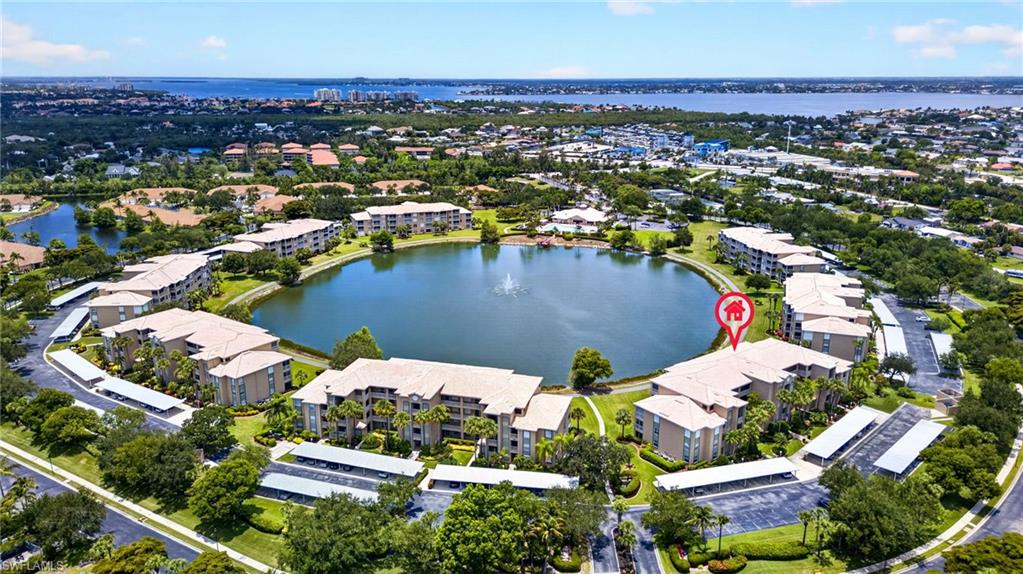 Community featuring a central lake with a fountain, surrounded by multi-story residential buildings with tile roofs
