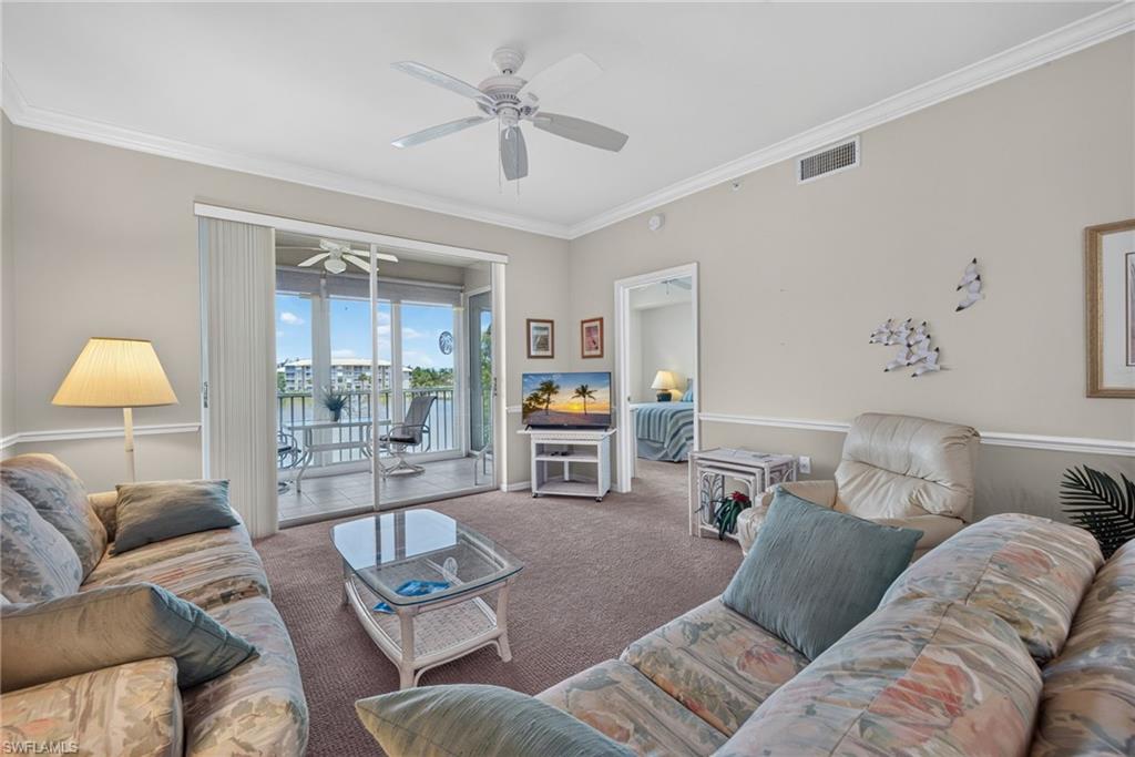 Living area featuring light neutral walls, crown molding, and carpeting