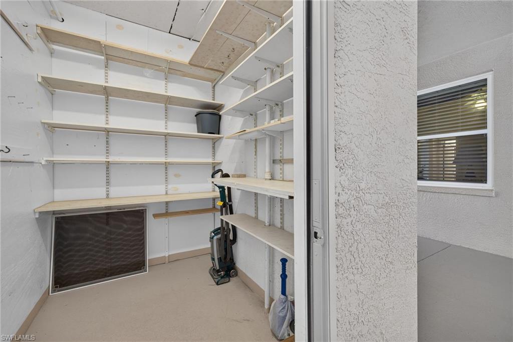 Utility closet featuring extensive built-in adjustable shelving, light beige flooring, and white wall finishes