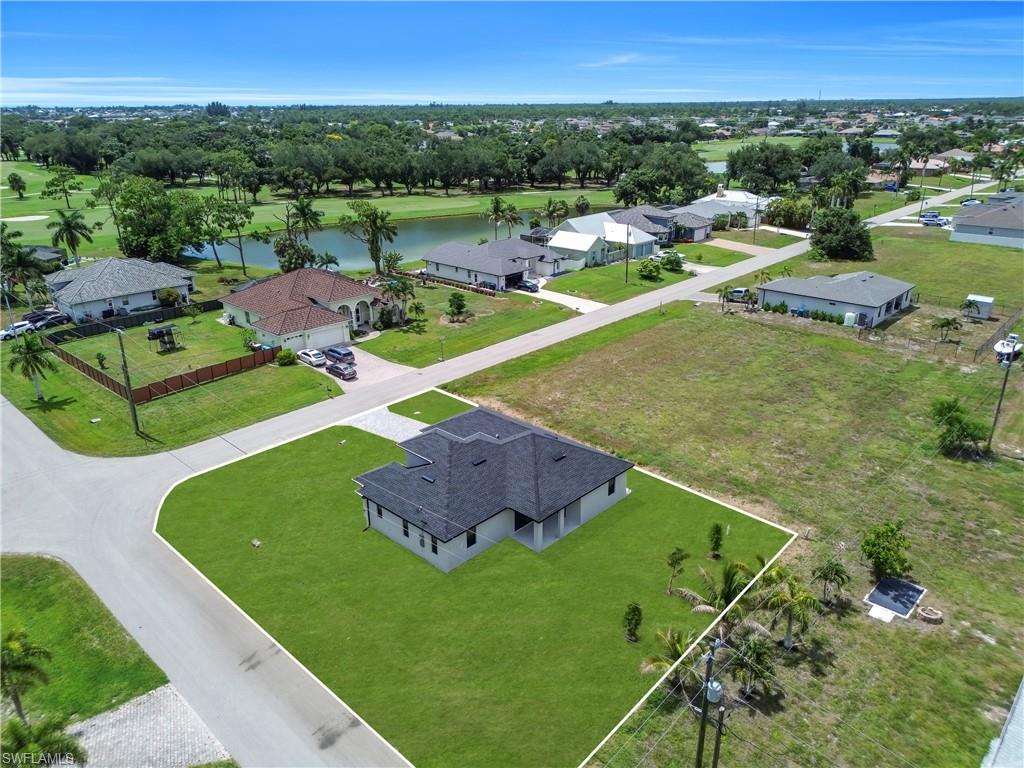 Newly constructed home with a dark shingle roof, light-colored exterior, and an expansive green lawn