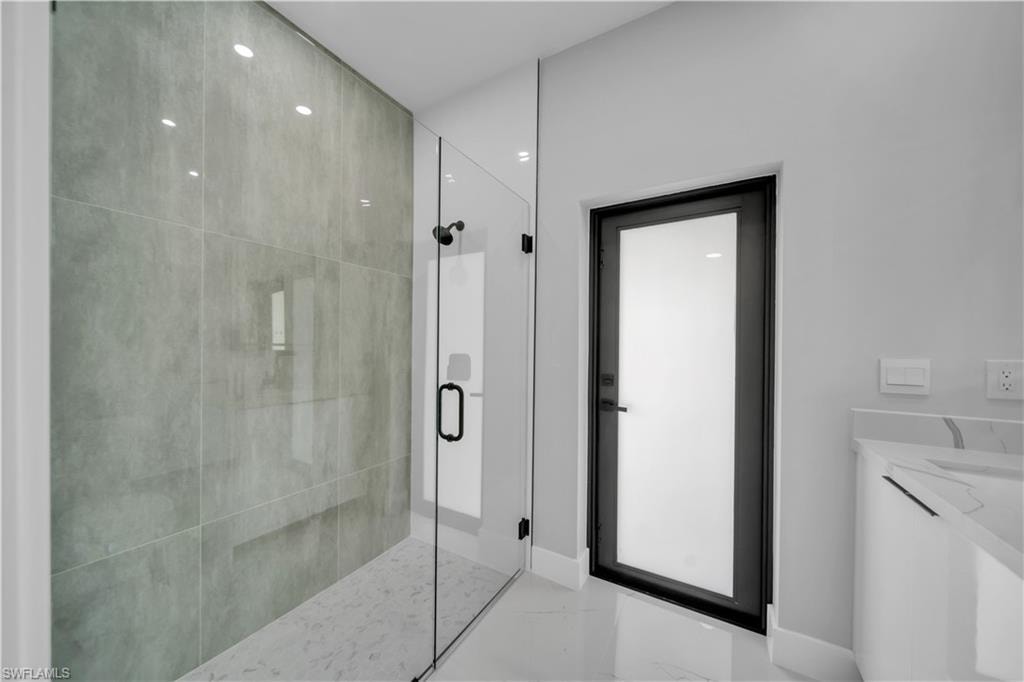 Spacious walk-in shower featuring large format grey tile, glass enclosure, and a built-in bench