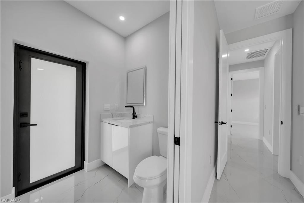 Modern bathroom featuring a contemporary vanity with a white countertop and black faucet, a framed mirror, and recessed lighting