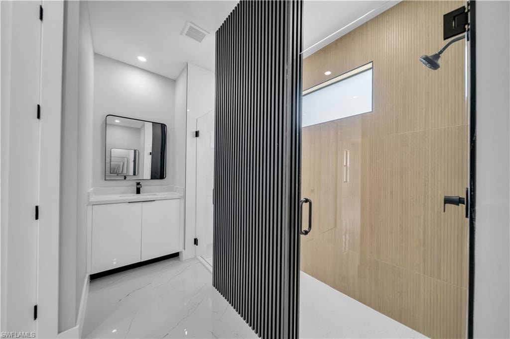 Contemporary bathroom featuring a sleek vanity with a rectangular sink, a black-framed mirror, and a glass-enclosed shower