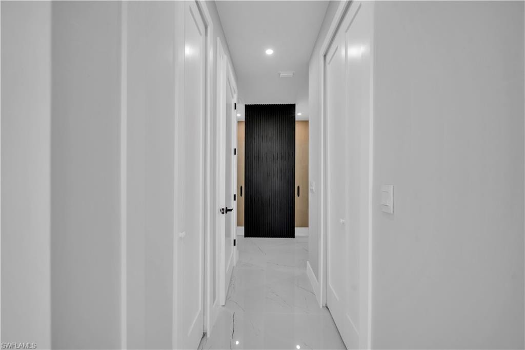 Hallway featuring white walls, white doors, recessed lighting, and large format tile flooring