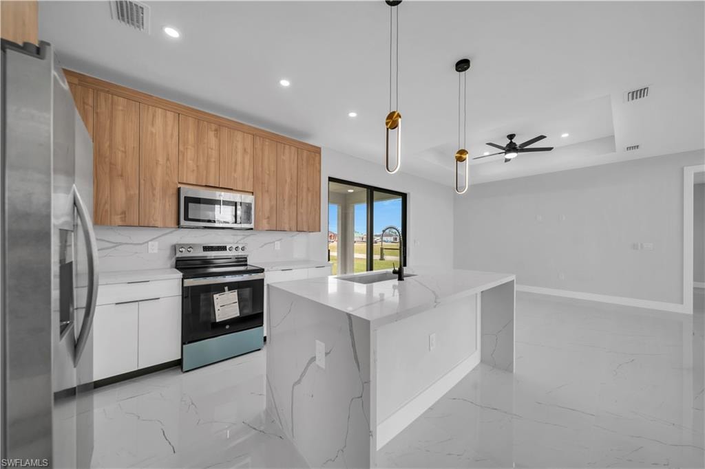 Contemporary kitchen featuring a waterfall island, white cabinetry, wood-finish upper cabinets, stainless steel appliances, and large format tile flooring