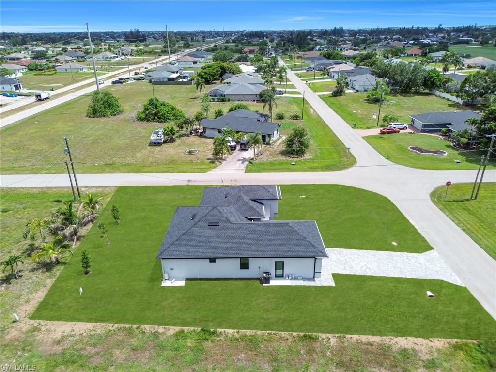 Newly constructed residence featuring a dark shingle roof, white exterior siding, and a light-colored paver driveway