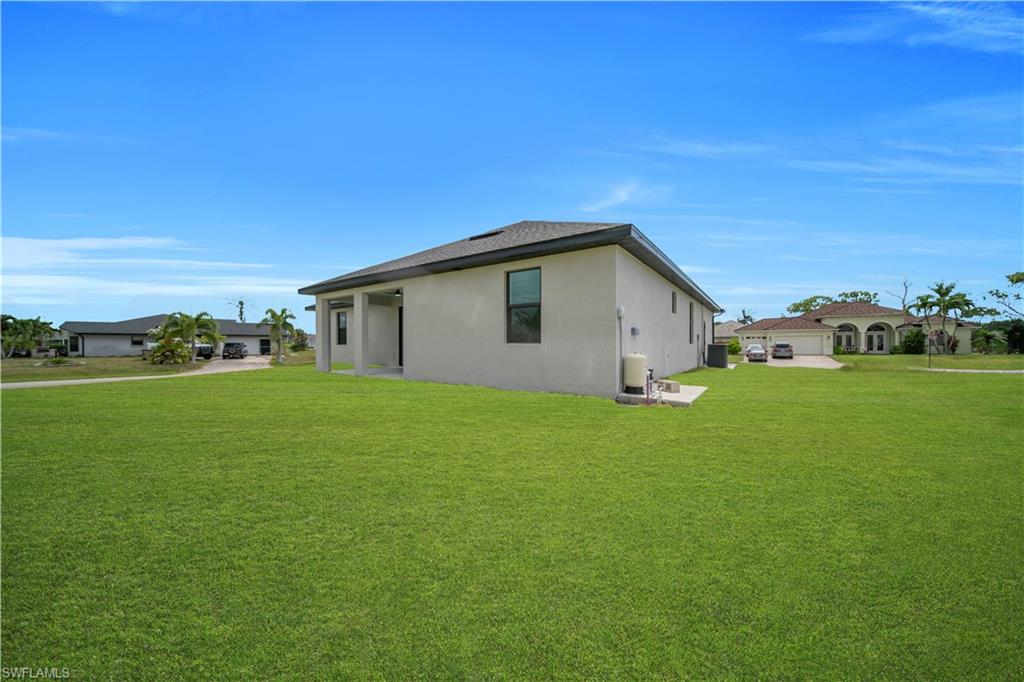 Expansive green lawn surrounds a contemporary stucco exterior with a dark shingle roof and a covered patio area