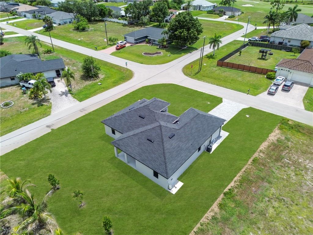 New construction residence featuring a dark shingle roof, light-toned exterior walls, and a paver driveway