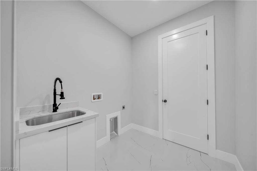 Laundry area featuring a utility sink with a matte black faucet, white cabinetry, and a stone-finish countertop
