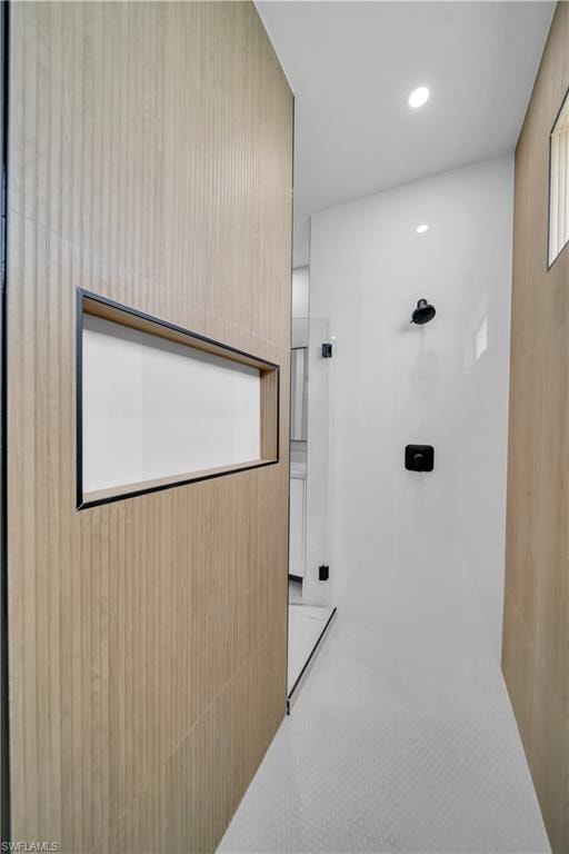 Modern shower enclosure featuring a wood-finish wall with an integrated niche