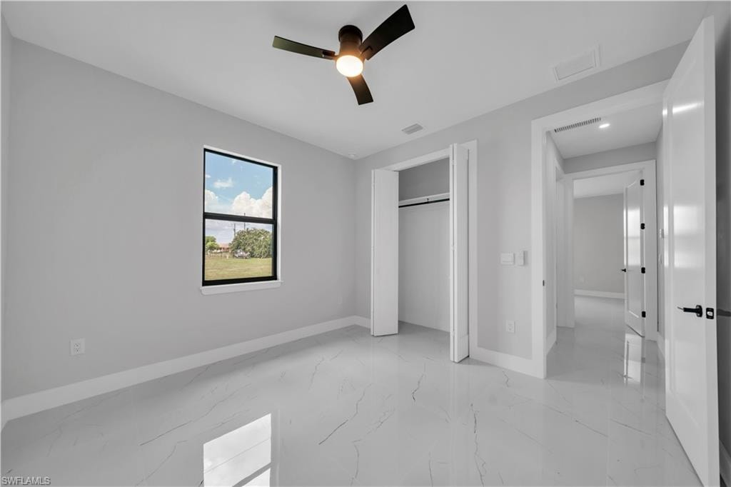 Spacious room featuring large format tile flooring, a contemporary ceiling fan, and a built-in closet with bifold doors