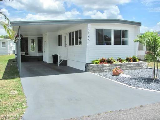 White-sided residence with multiple windows and a gray-painted driveway