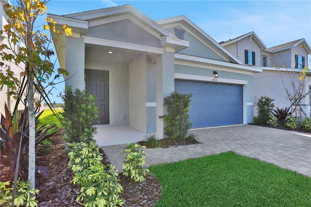 View of front of home with stucco siding, decorative driveway, a garage, and a front lawn