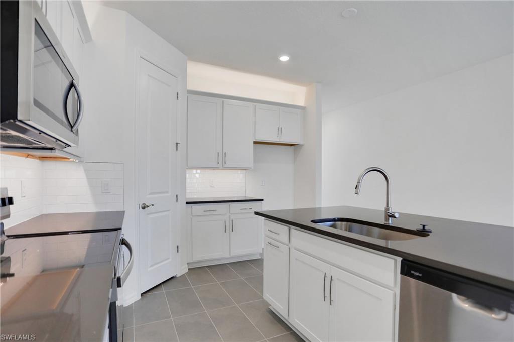 Kitchen with stainless steel appliances, white cabinets, decorative backsplash, light tile patterned flooring, and recessed lighting