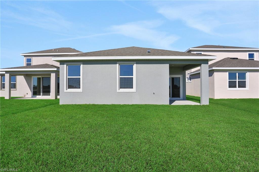 Rear view of property with a patio area, a lawn, stucco siding, and a shingled roof
