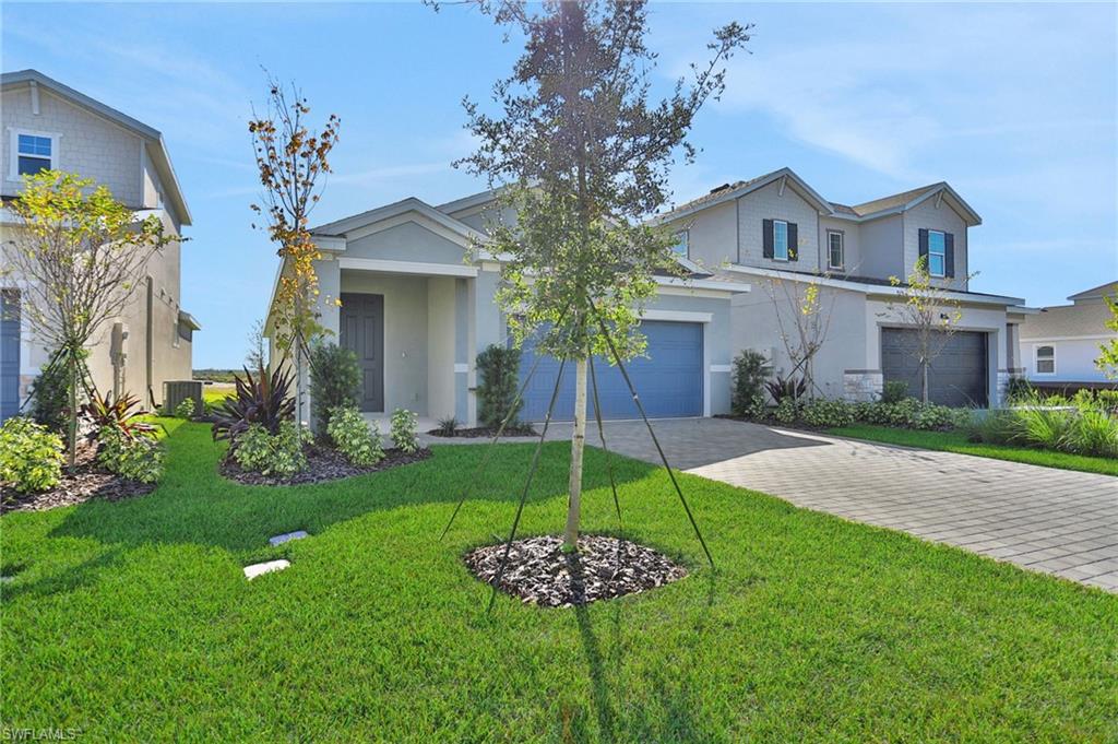 View of front facade featuring decorative driveway, stucco siding, and a front yard